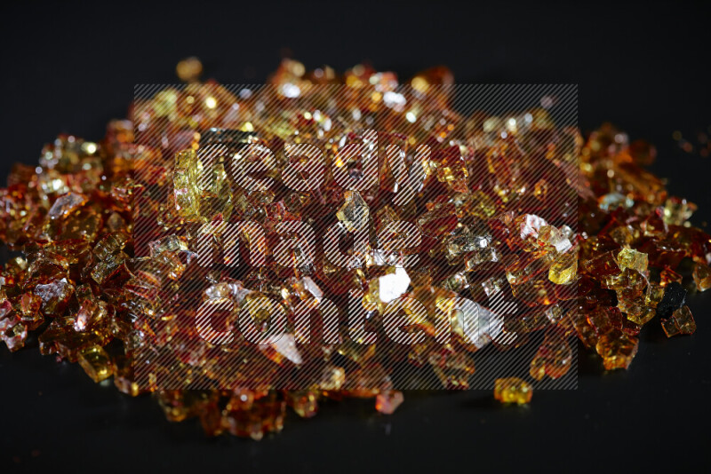 Transparent orange fragments of glass scattered on a black background