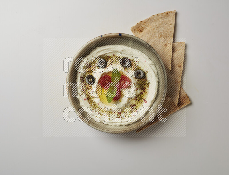 Lebnah garnished with cherry tomato, mint, olives & pine nuts in a grey pottery plate on a white background