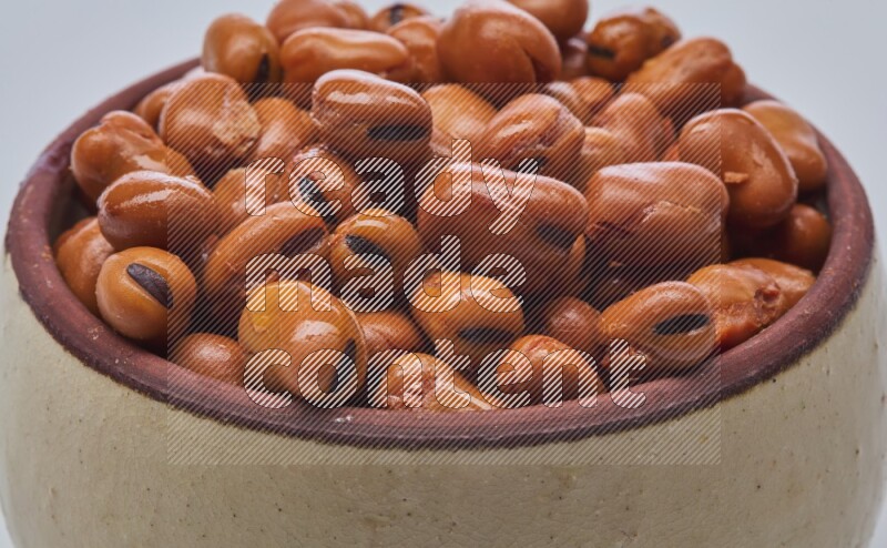 Close up shot of cooked fava beans (foul) in a container on white background