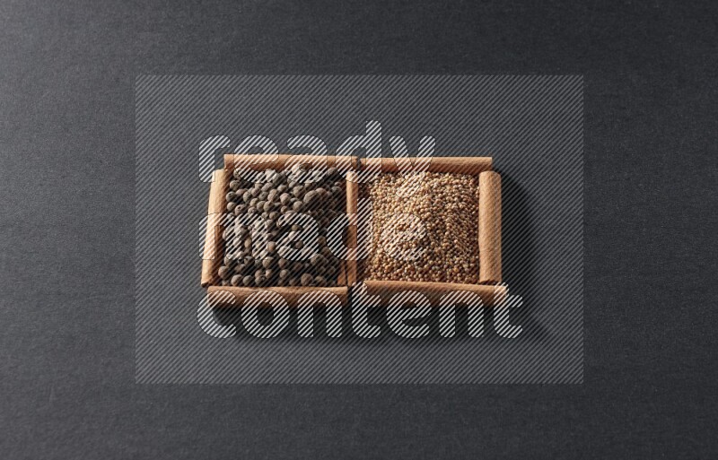 مربعان من أعواد القرفة ممتلئان بحبوب الخردل وحبوب بهار الفلفل الحلو علي خلفية سوداء