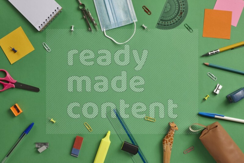 Different school supplies on green background