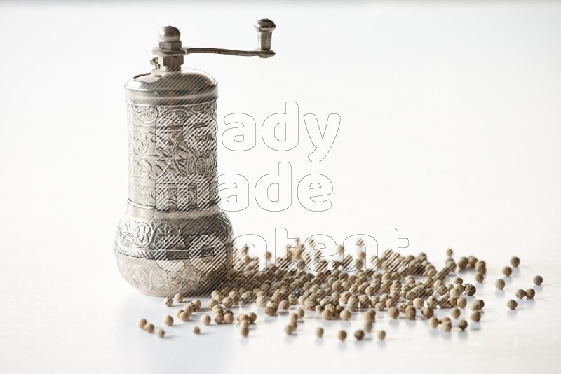 White pepper beads with a metal grinder on white flooring