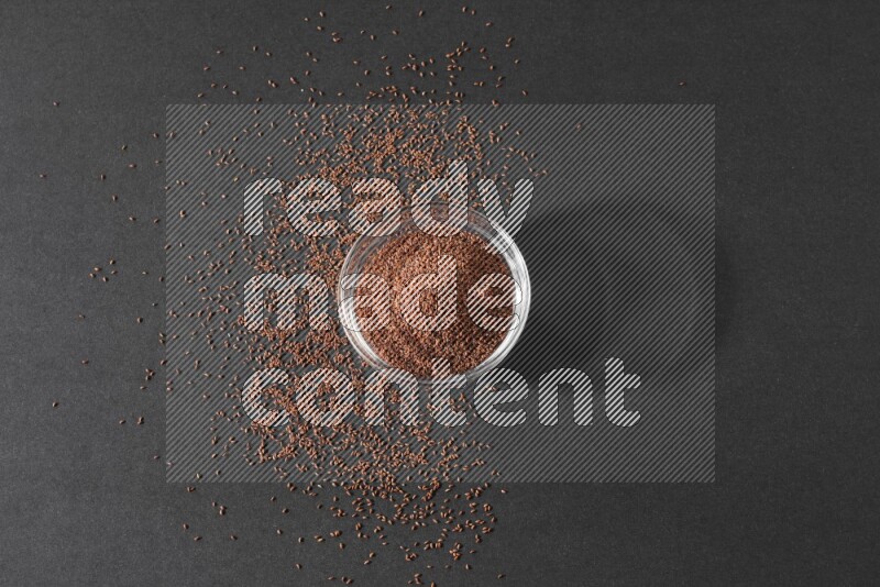 وعاء زجاجي ممتلئ ببذور حب الرشاد محاط بالبذور على أرضية سوداء