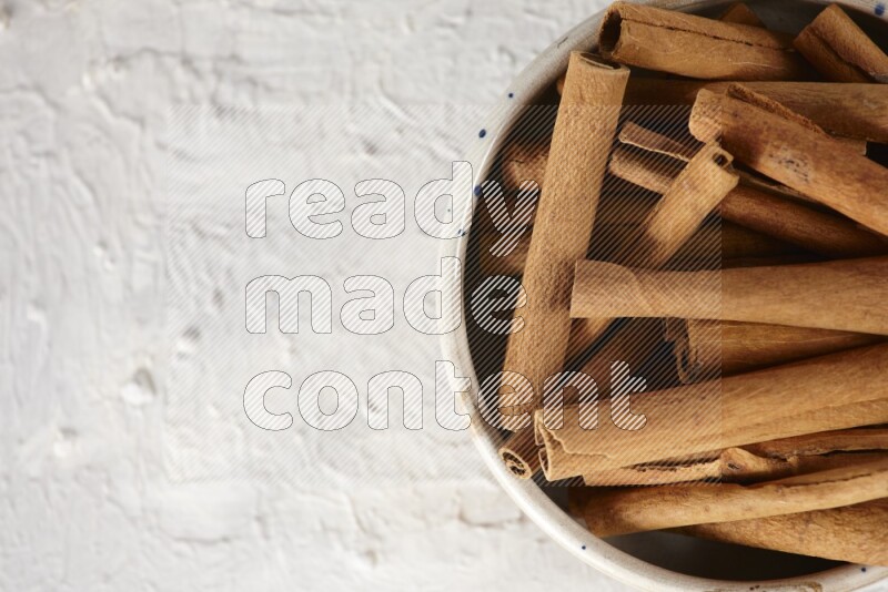 Cinnamon sticks in a ceramic bowl in different angles on white background