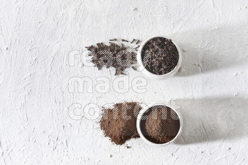 وعاءين من السيراميك بيج اللون، أحدهما مملوء بالقرنفل والآخر مملوء بالبودرة على أرضية بيضاء