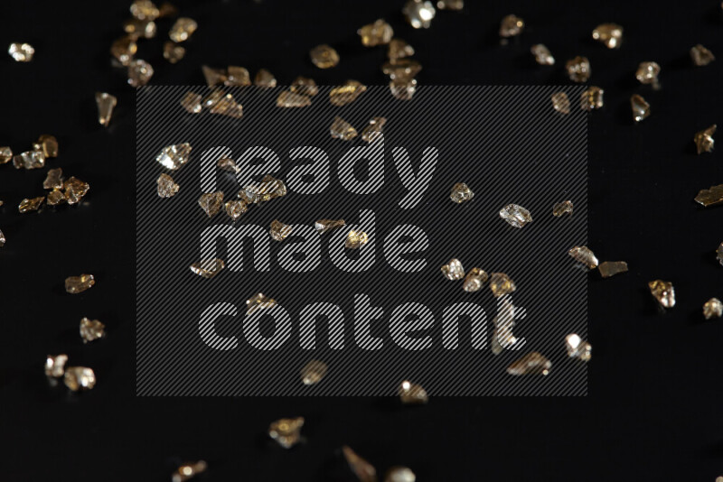 Gold shimmering fragments of glass scattered on a black background