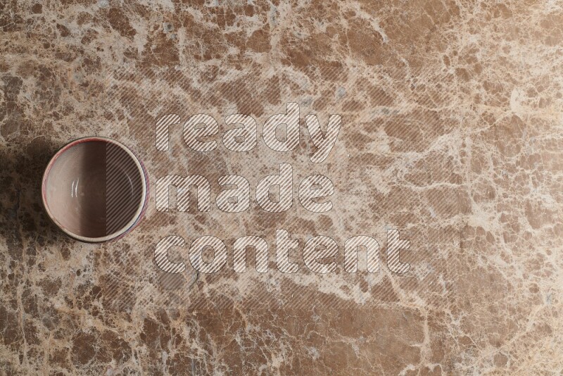 A multicolored pottery bowl on beige marble background