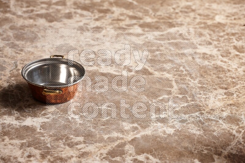A small copper pot on beige marble background