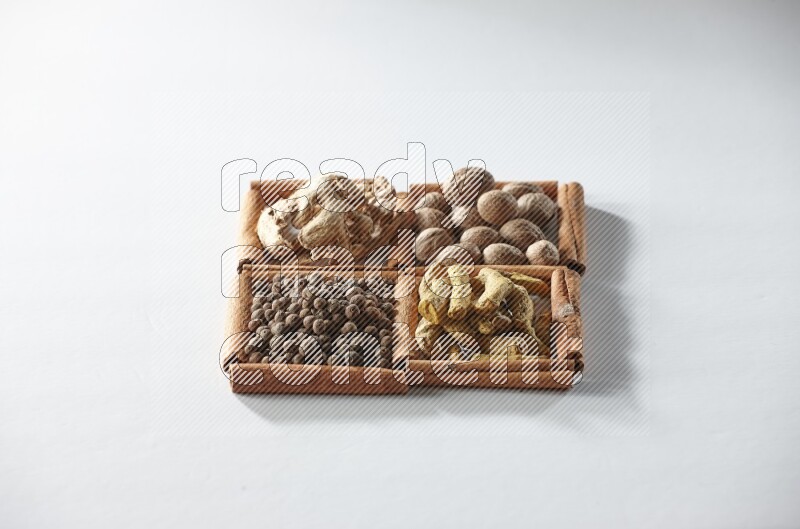 4 squares of cinnamon sticks full of nutmegs, dried ginger, turmeric fingers and allspice on white flooring