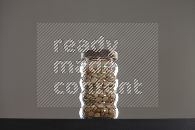 Fava beans in a glass jar on black background
