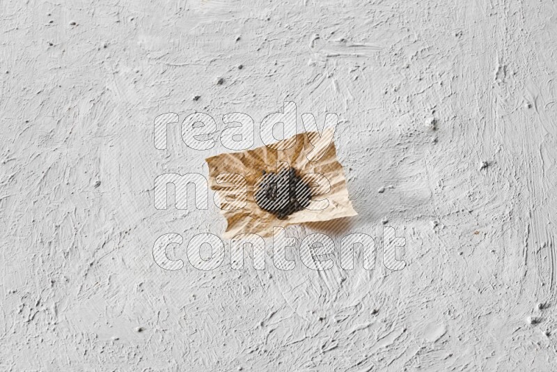 Black pepper on a crumpled paper on a textured white flooring
