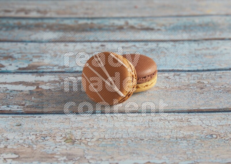 45º Shot of of two assorted Brown Irish Cream, and Yellow, and Brown Chai Latte macarons  on light blue background