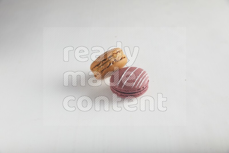 45º Shot of of two assorted Brown Irish Cream, and Red Poppy Flower macarons on white background