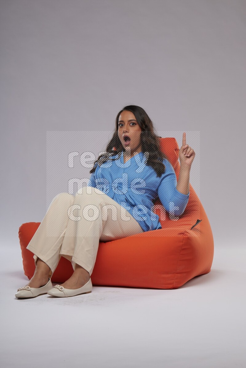 A woman sitting on an orange beanbag and interacting with the camera