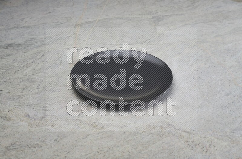 A black ceramic circular plate on grey marble background