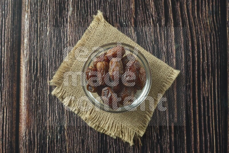 Dates in different bowls (wooden, pottery and glass) on wooden background