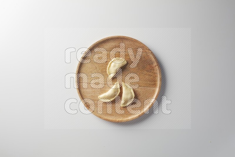 Three Sambosas on a wooden round plate on a white background