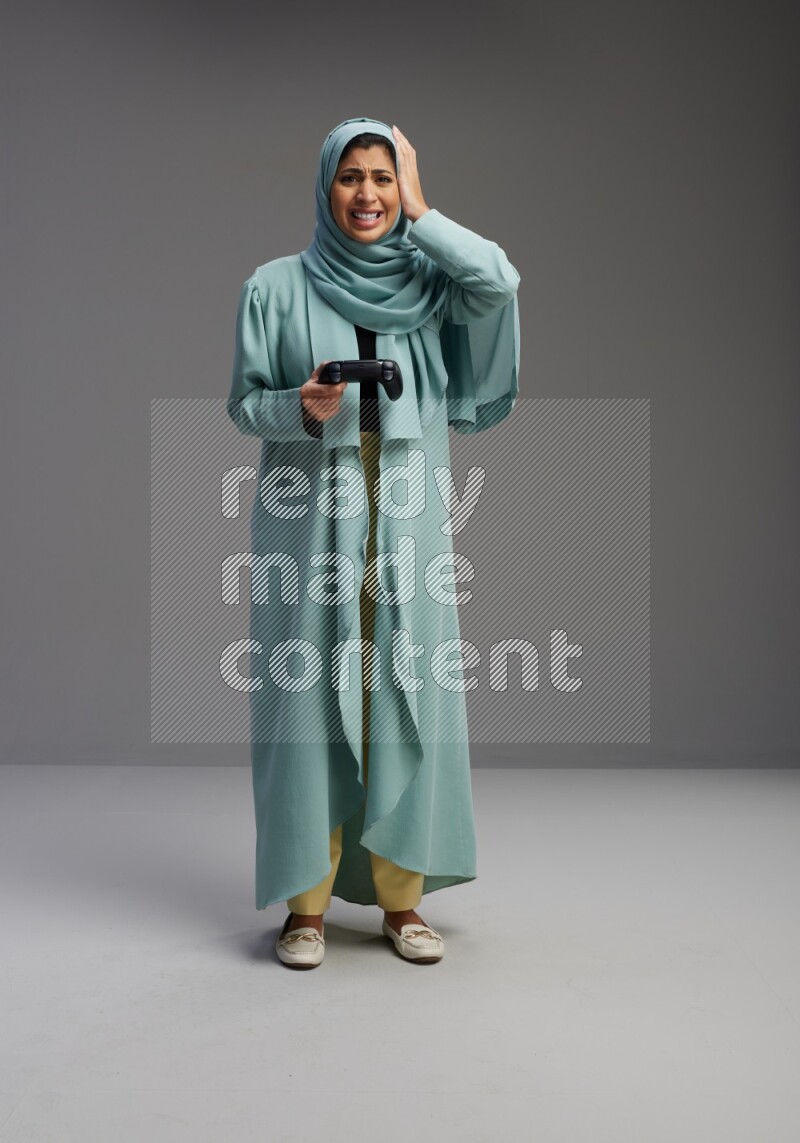 Saudi Woman wearing Abaya standing Playing Games on Gray background