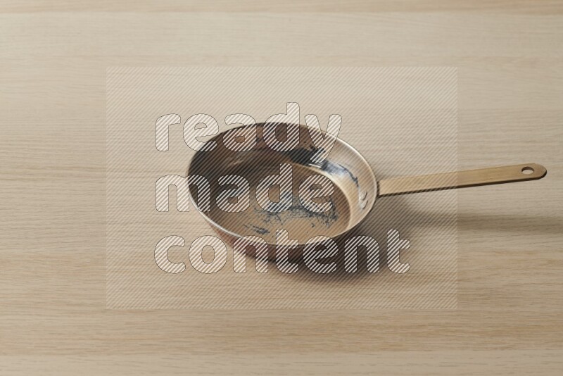 A small copper pan on light wooden background