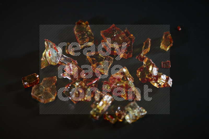 Transparent orange fragments of glass scattered on a black background