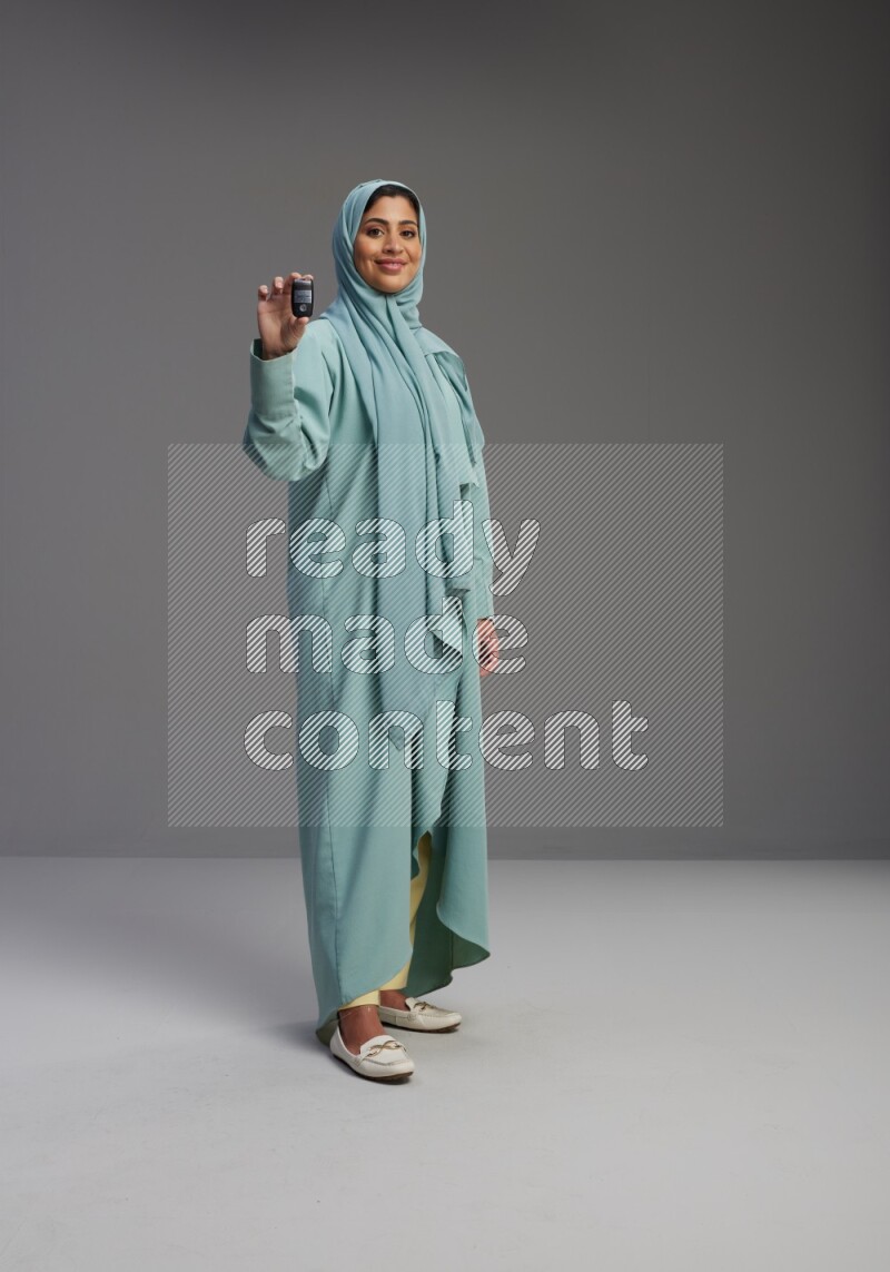 Saudi Woman wearing Abaya standing holding car key on Gray background