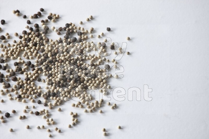 حبوب الفلفل المختلطة السوداء والبيضاء على أرضية بيضاء