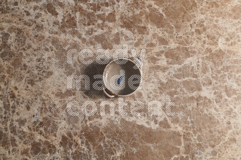 A multicolored pottery bowl on beige marble background