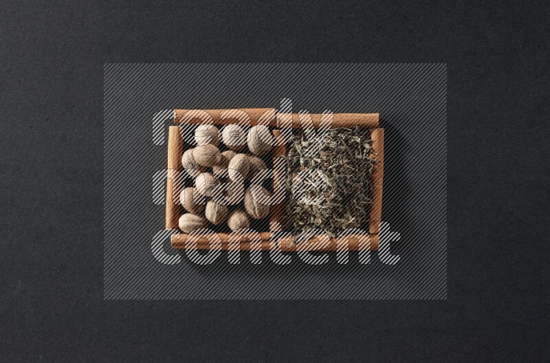2 squares of cinnamon sticks full of nutmegs and dried basil on black flooring