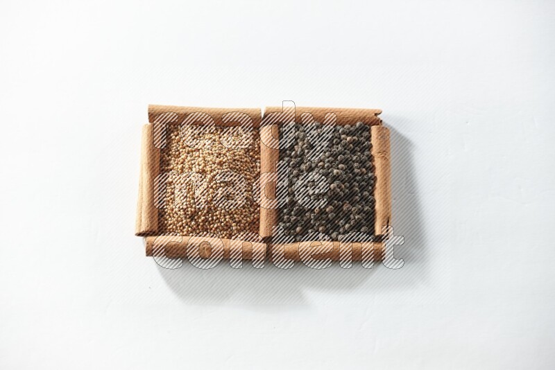 2 squares of cinnamon sticks full of mustard seeds and black peppers on white flooring