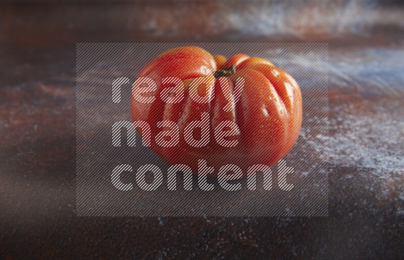 45 degree single heirloom tomato on  a textured reddish rustic metal background