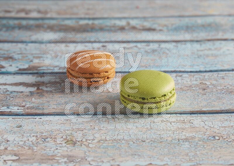 45º Shot of of two assorted Brown Irish Cream, and Green Pistachio macarons  on light blue background