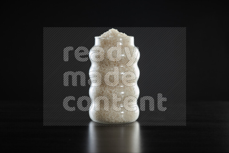 White rice in a glass jar on black background