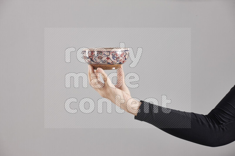 A woman in black abaya holding different pottery essentials in different positions