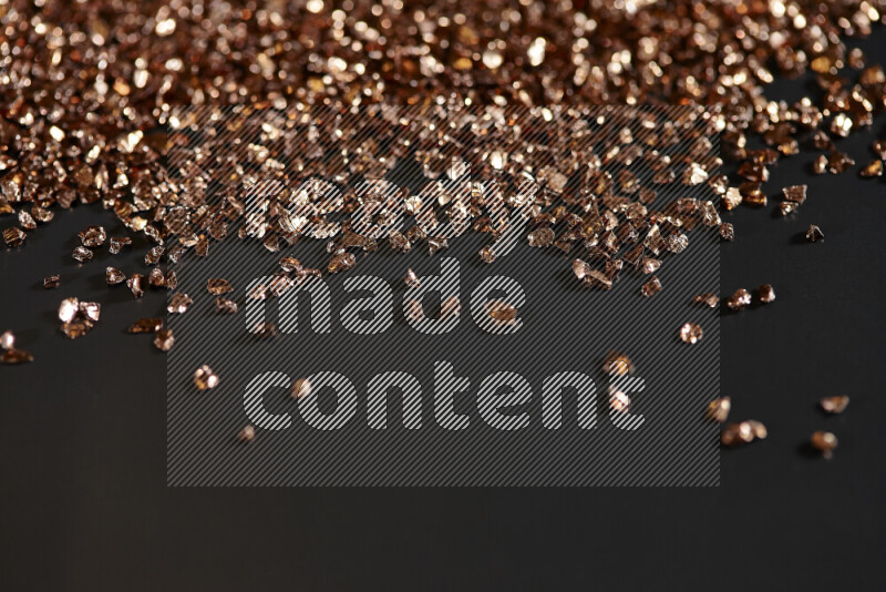 Bronze shimmering fragments of glass scattered on a black background