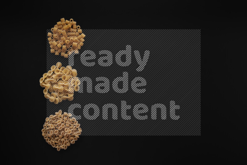 Different pasta types in 3 bunches on black background