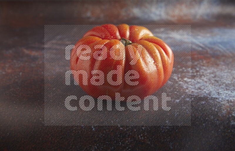 45 degree single heirloom tomato on  a textured reddish rustic metal background