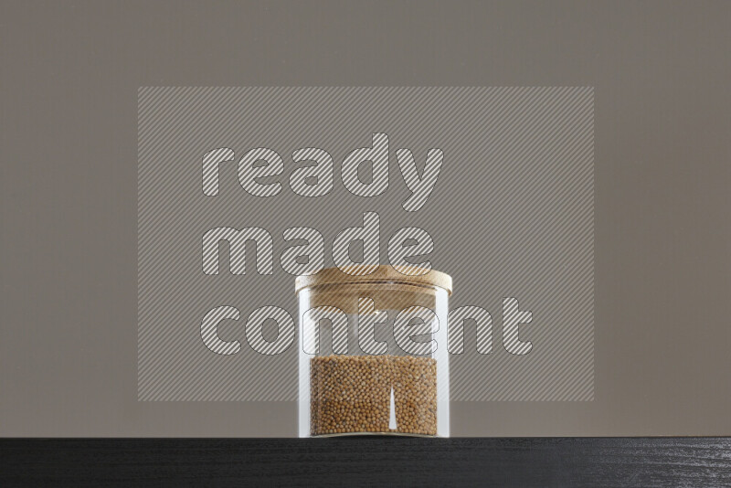 بذور الخردل في وعاء زجاجي على خلفية سوداء