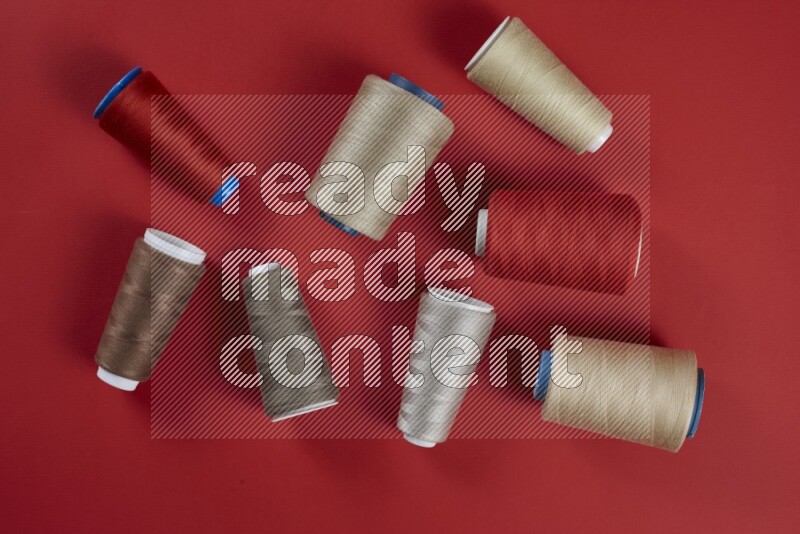 A brown and red collection of sewing and tailoring tools arranged on a red background