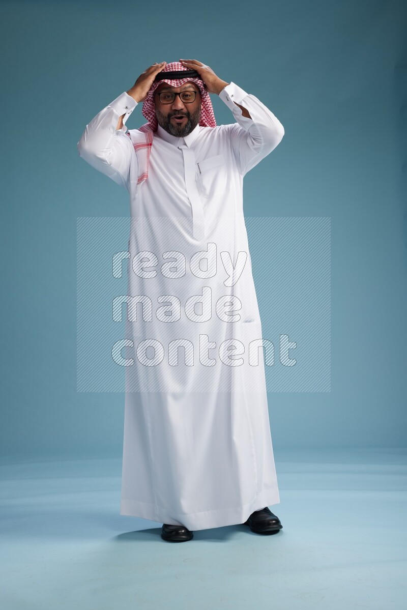 Saudi Man with shimag Standing Interacting with the camera on blue background