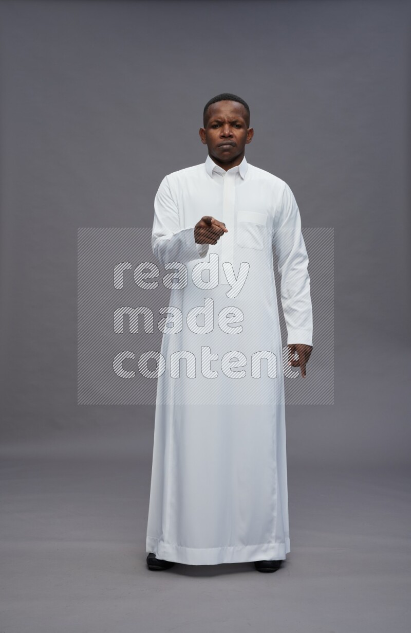 Saudi man wearing thob standing interacting with the camera on gray background