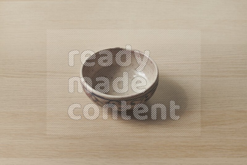 A multicolored pottery bowl on light wooden background