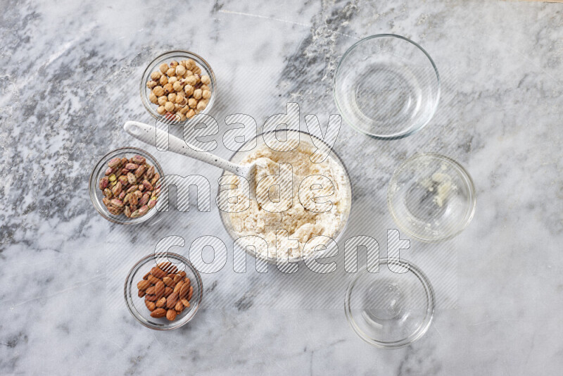 Ghoriba step by step with its ingredient, flour, powdered sugar, ghee and nuts on grey marble background
