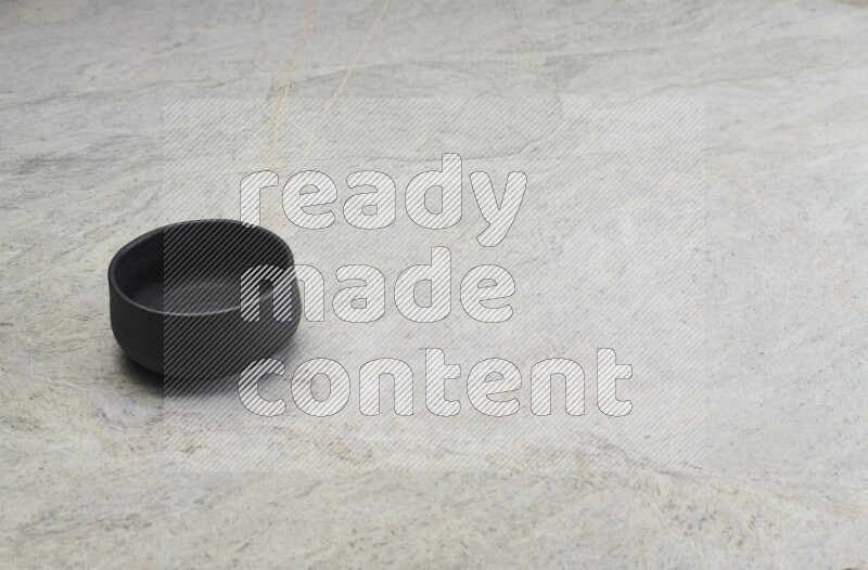 A black pottery bowl on grey marble background