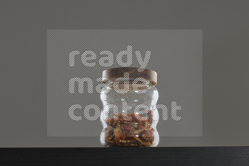 Chili pepper in a glass jar on black background