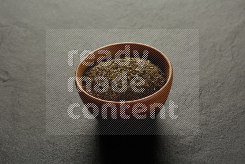 wooden round sauce bowl filled with herbs on grey textured countertop
