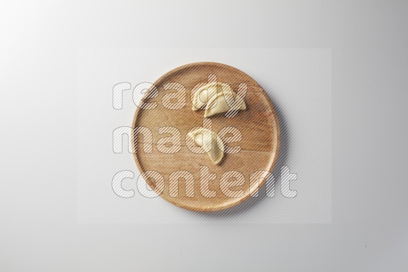 Three Sambosas on a wooden round plate on a white background