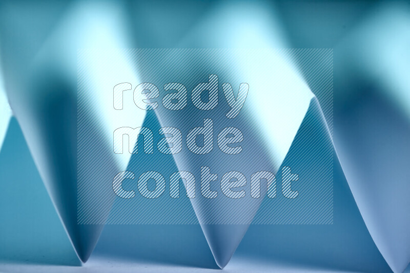 A close-up abstract image showing sharp geometric paper folds in blue gradients