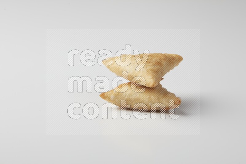 Two fried sambosas on a white background