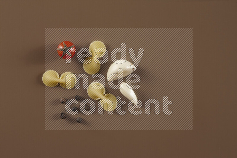 Raw pasta with different ingredients such as cherry tomatoes, garlic, onions, red chilis, black pepper, white pepper, bay laurel leaves, rosemary and cardamom on beige background