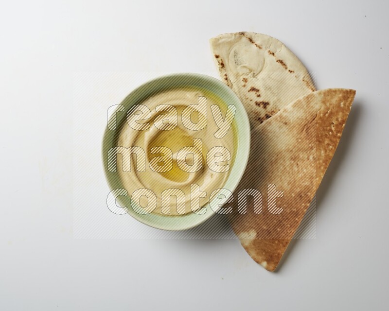 Hummus in a green plate garnished with olive oil on a white background